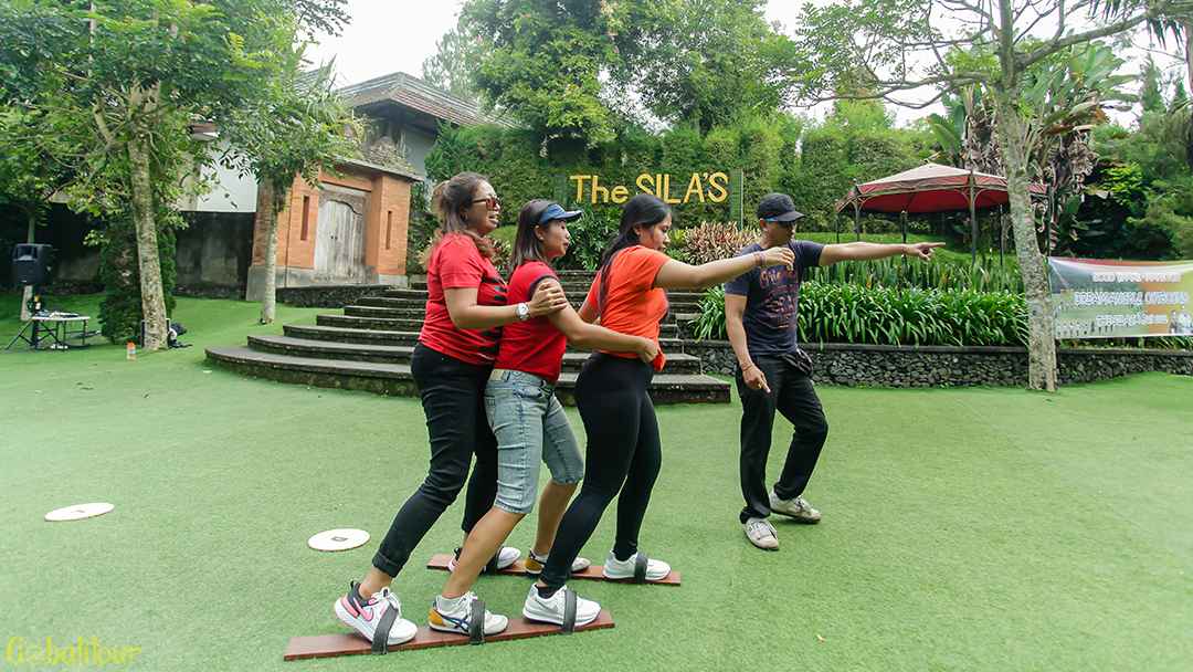 Peserta outbound Bali mengikuti permainan Bakiak Race untuk melatih kerjasama.