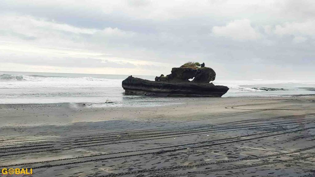Pantai Yeh Gangga di Tabanan Bali dengan ombak besar, formasi batu tebing, dan pemandangan sunset memukau.